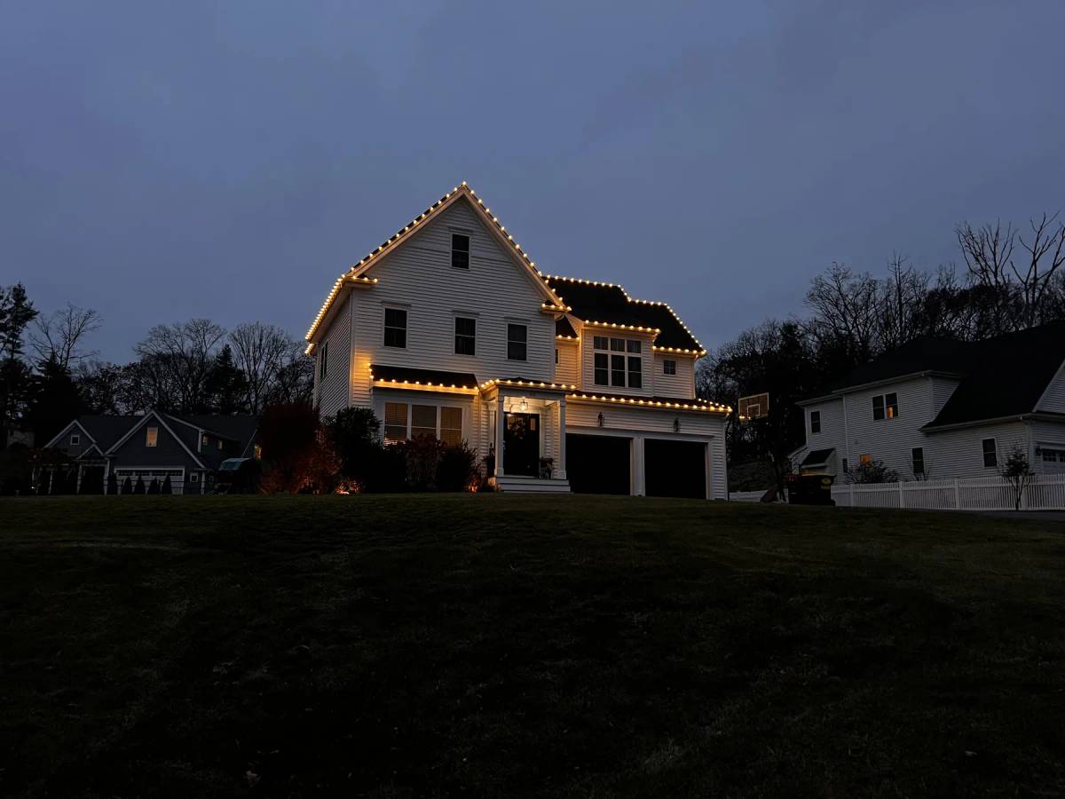 Warm white holiday roofline on a farmhouse at dusk